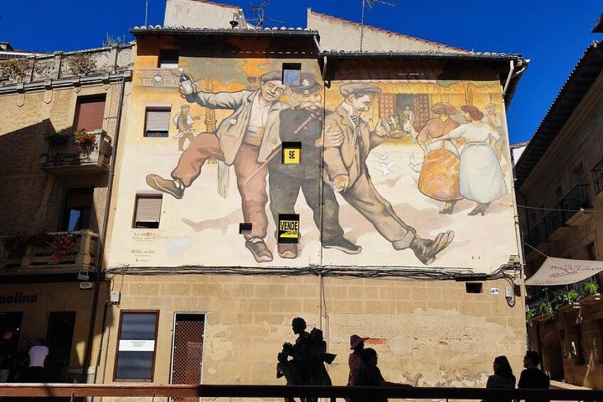 A mural on a building with figures and text. 2