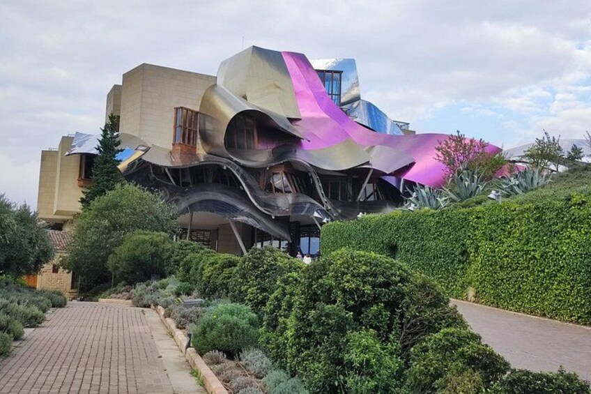 Ein modernes Gebäude mit einer gewundenen Fassade und einem Weg, der davorführt. 2