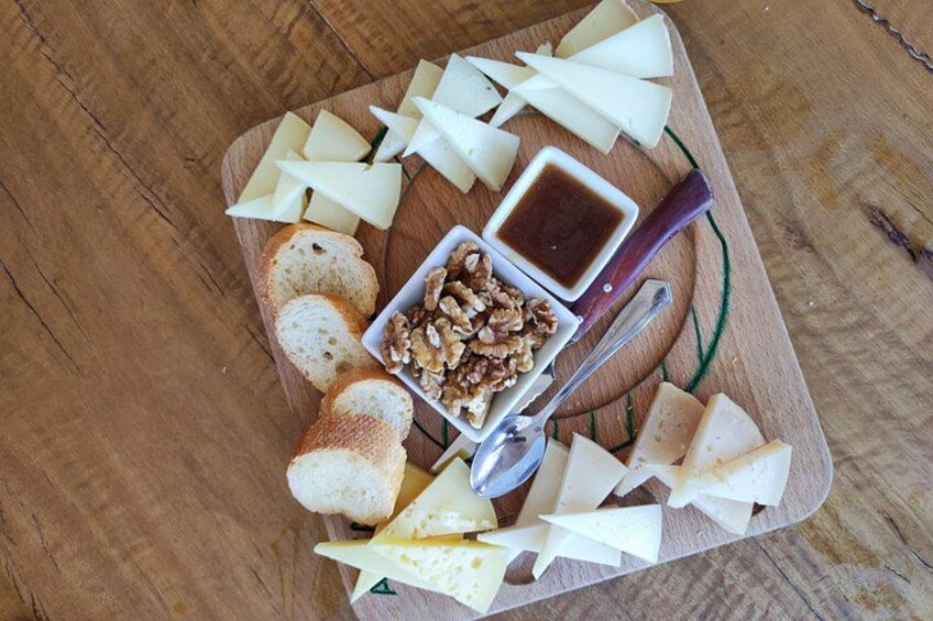 Une planche en bois garnie de fromage, de pain, de noix et d’un petit ramequin de sauce. 4