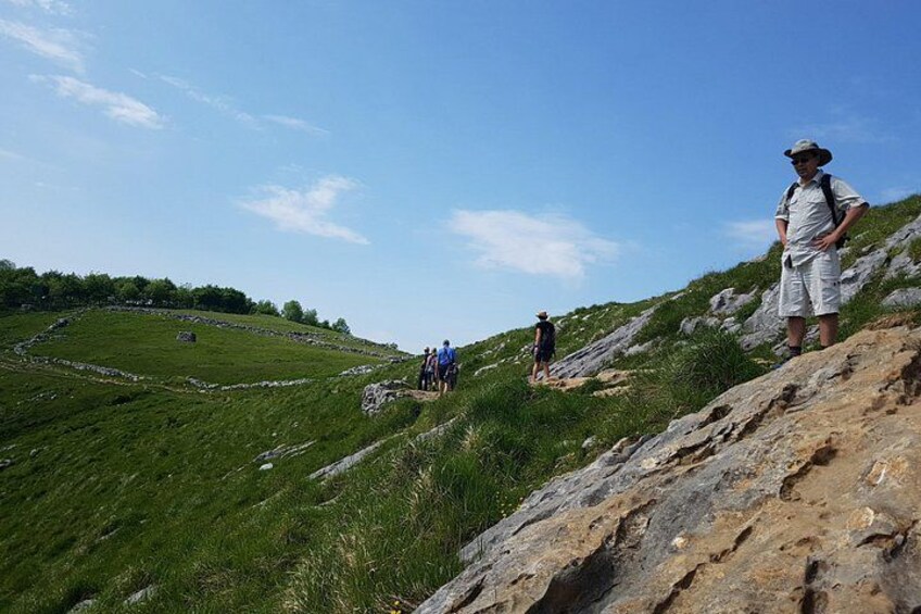A hilly landscape with a stone wall and a grassy area. 3
