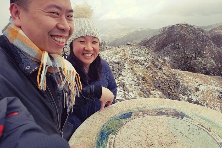 A person holding a map with a mountainous landscape in the background. 2