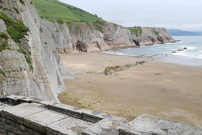 Un paysage côtier avec des falaises, une plage de sable et un escalier en pierre. 2
