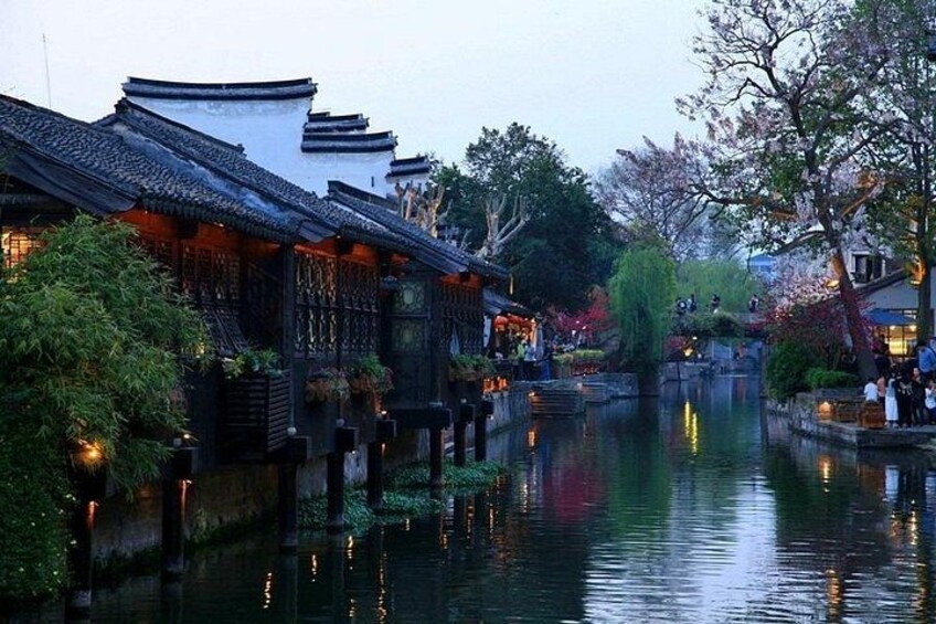 A traditional Chinese courtyard with buildings, a water canal, and cherry blossoms. 4