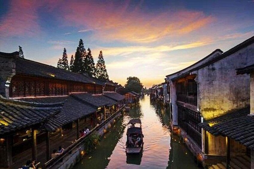 A narrow waterway flanked by traditional buildings with tiled roofs, reflecting the sky. 5