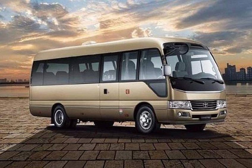 A beige van parked on a paved surface with a sunset sky in the background. 3