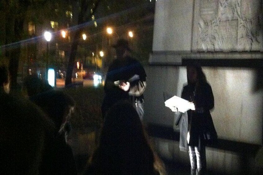 A nighttime scene with a monument and people walking by. 3