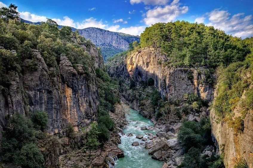 Un fiume che scorre attraverso un canyon con ripide pareti rocciose e vegetazione lussureggiante. 3