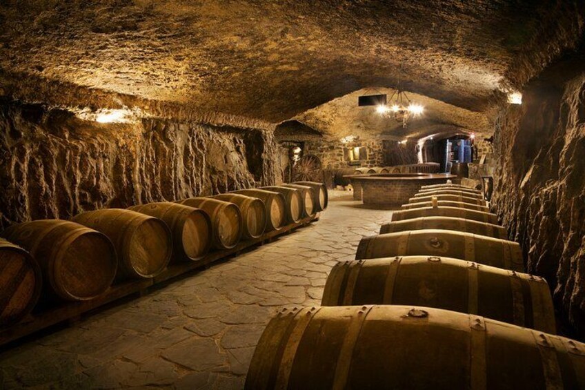 Una cantina con file di botti di legno, pareti in pietra e pavimento in pietra. 3