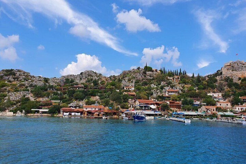A coastal town with buildings, boats, and a hilly landscape. 2