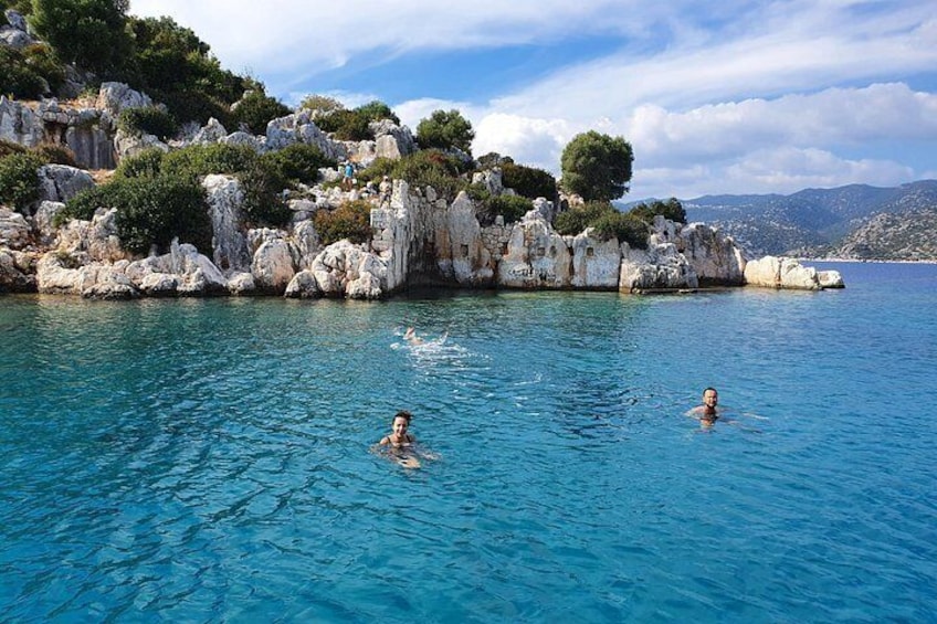A clear blue sea with rocky cliffs and greenery in the background. 5