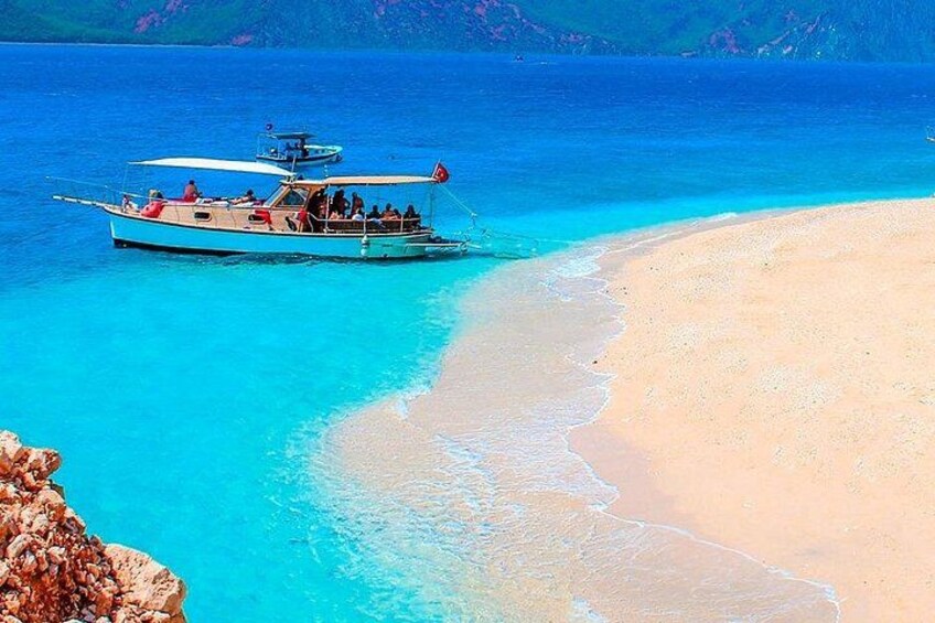 Een boot op een turquoise strand met helder water en een rotsachtige kustlijn. 3