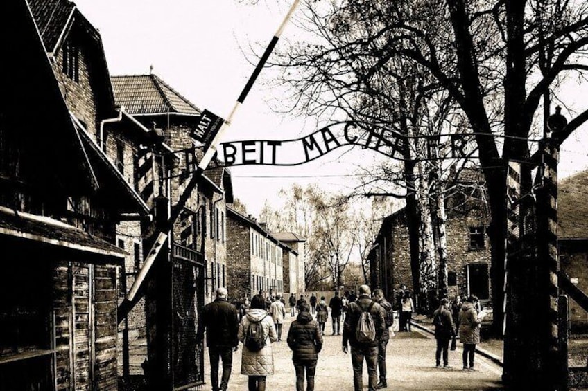 A street with people walking, wooden buildings, and a sign that reads 'BEIT MACHT'. 1