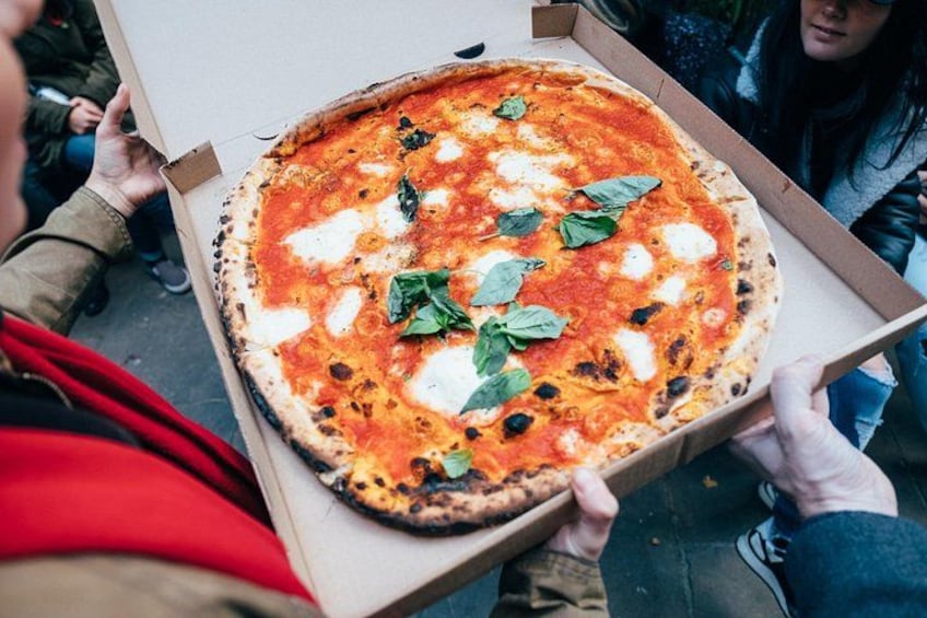 En person holder en stor pizzabakke med en pizza i. 5