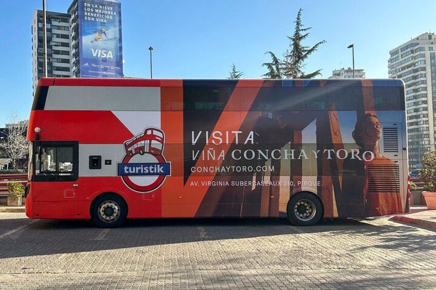 A red and white bus with a large advertisement for a visit to Conchaytor. 1