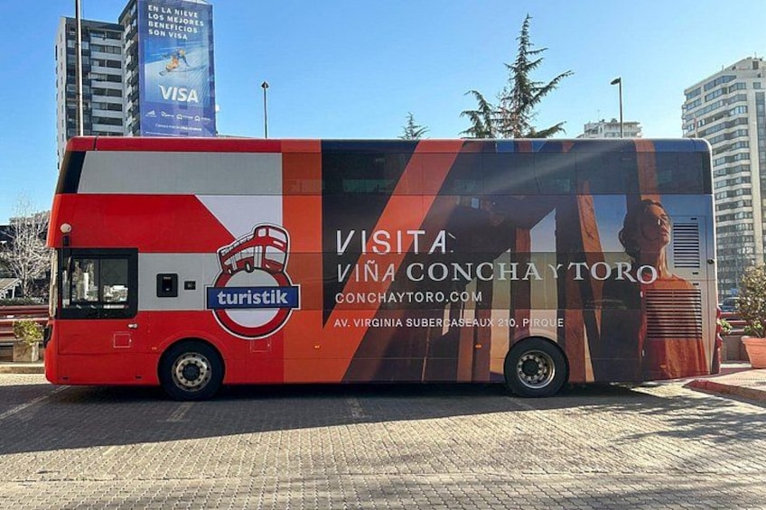 A red and white bus with advertisements for tourism and a Visa sign in the background. 1