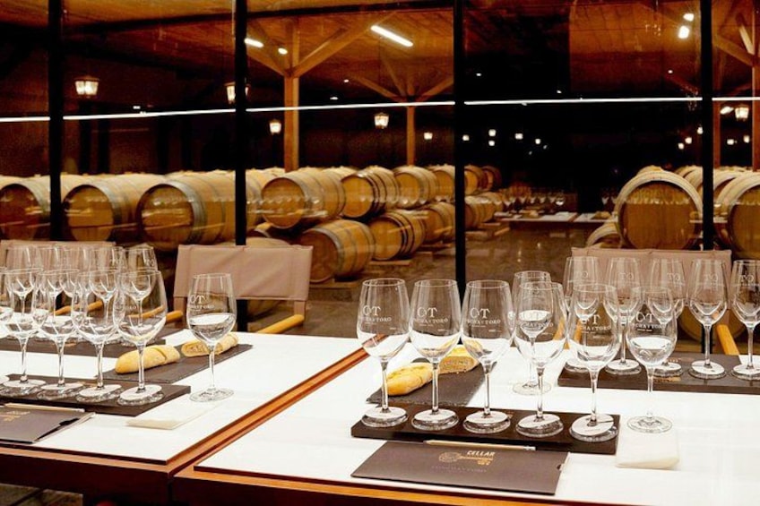 A wine tasting event with empty wine glasses and bread on a table, set against a backdrop of wine barrels. 5