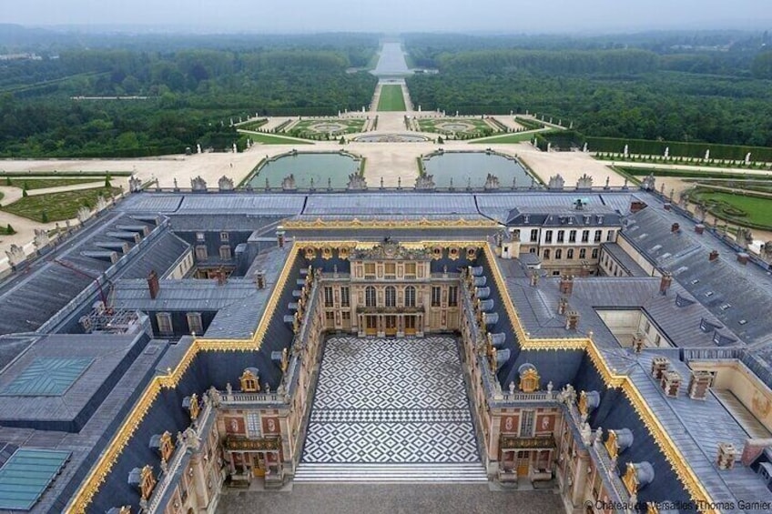 A grand palace with symmetrical architecture, a central courtyard with a fountain, and a formal garden in the background. 3