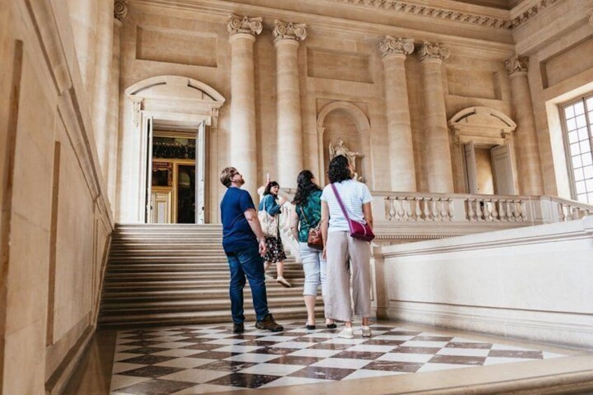A grand staircase with marble columns and a checkered floor. 4