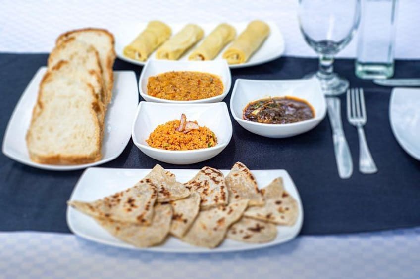 A meal with bread, rolls, and various sauces on a table. 4