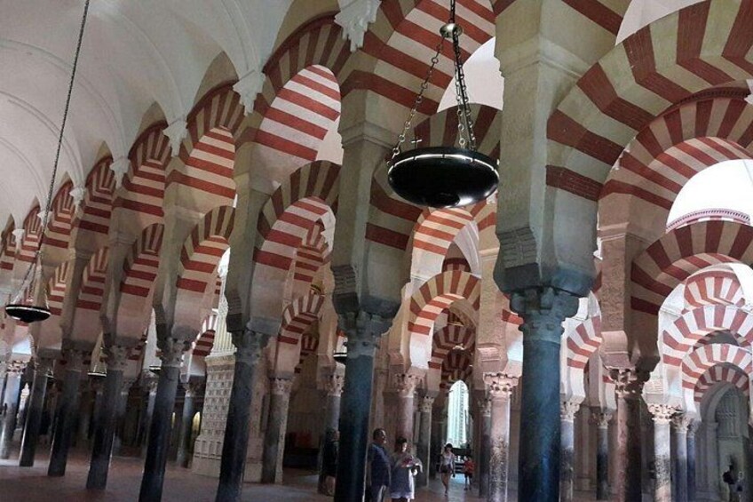 A mosque interior with red and white striped arches and columns. 2