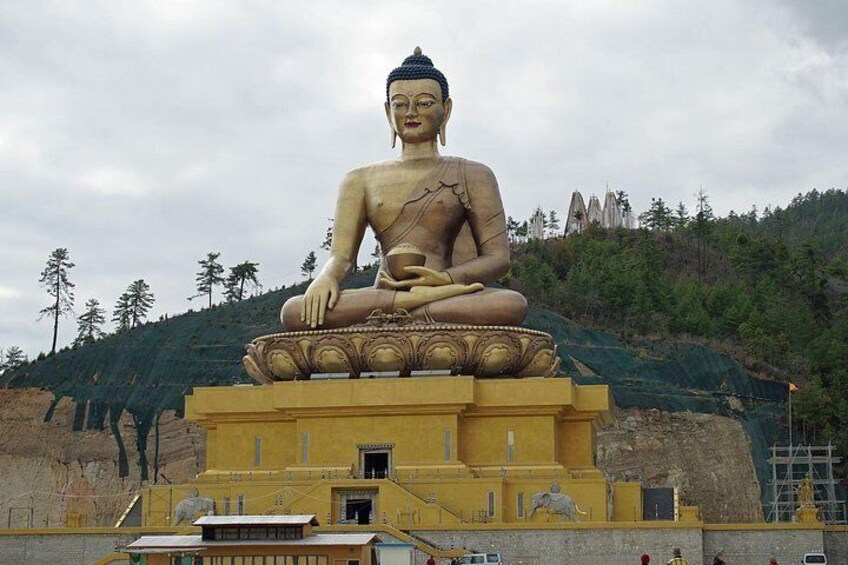 Une grande statue de Bouddha, assise sur un piédestal, avec une chaîne de montagnes en arrière-plan. 4