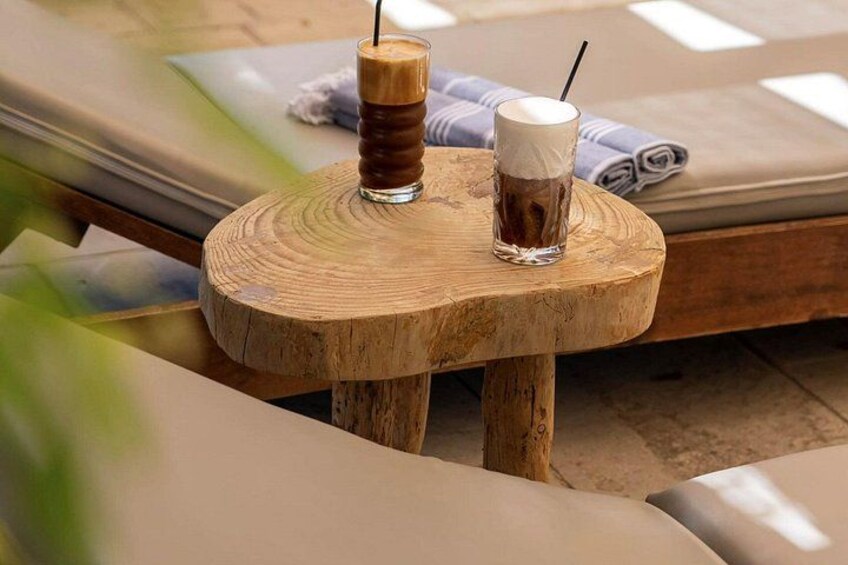 Une table en bois avec deux verres de café glacé, une serviette et, au fond, une chaise longue. 5