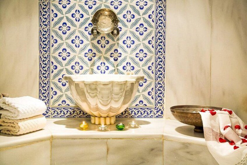 Un bagno con un lavandino grande e decorativo, una vivace decorazione a mosaico sulle pareti e una ciotola con petali di rosa. 2