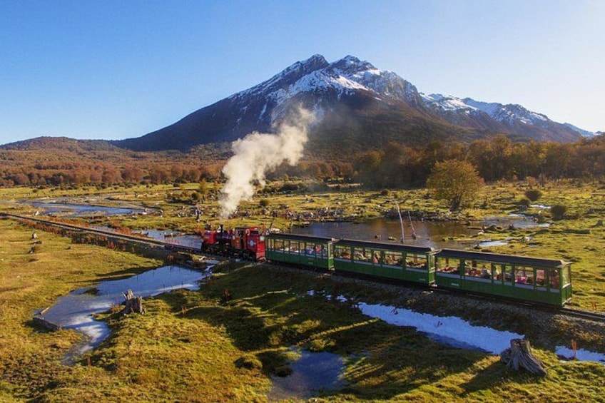 Een stoomtrein rijdt door een vallei met een berg op de achtergrond. 1