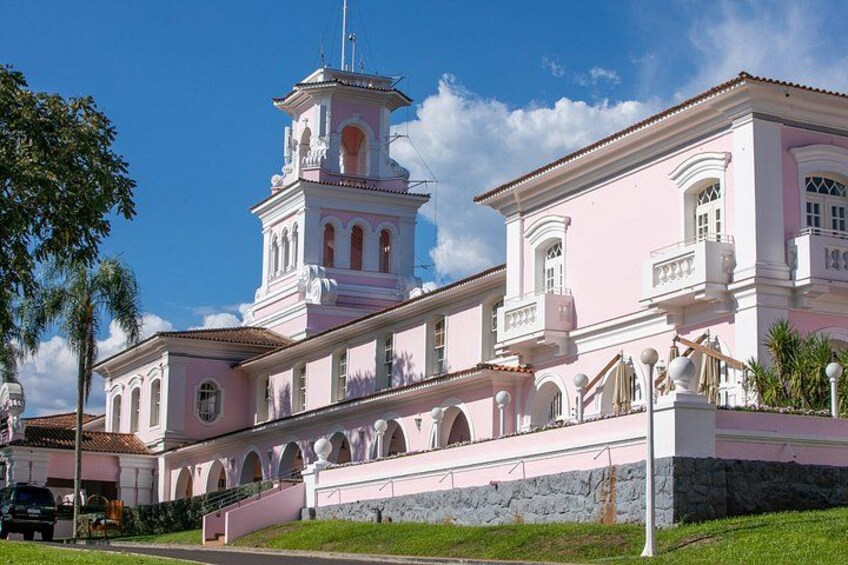 Un edificio de estilo colonial rosa con una torre de campanas, ventanas arqueadas y una base de piedra. 1