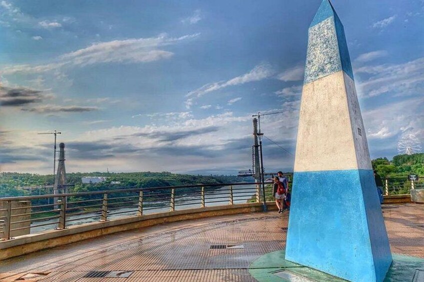 Un puente con un monumento azul y blanco, un río y colinas distantes. 4