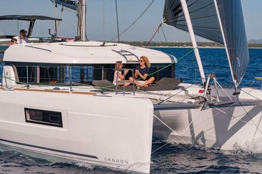 A white sailboat with a cabin, named 'LAGOON,' on calm waters. 5