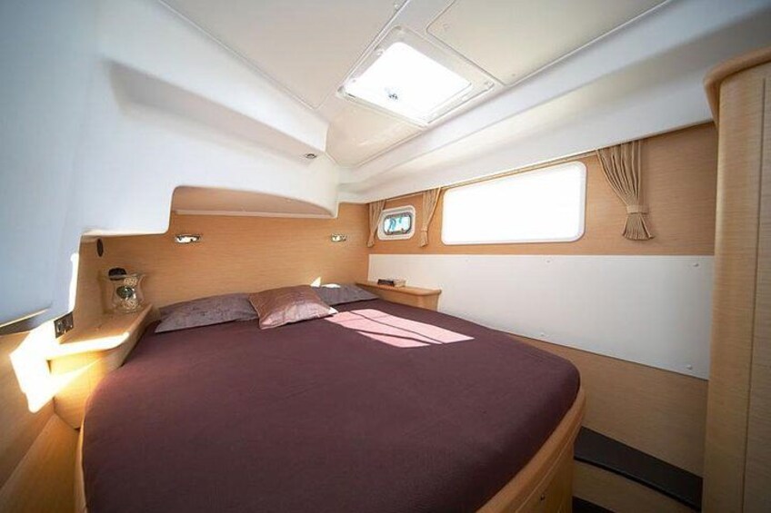 A cabin interior with a bed, a window, and a control panel. 2