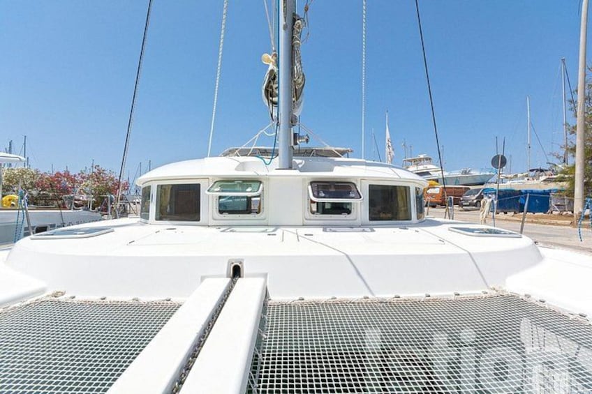 A white yacht with a cabin and a mast, docked at a marina with other boats. 4
