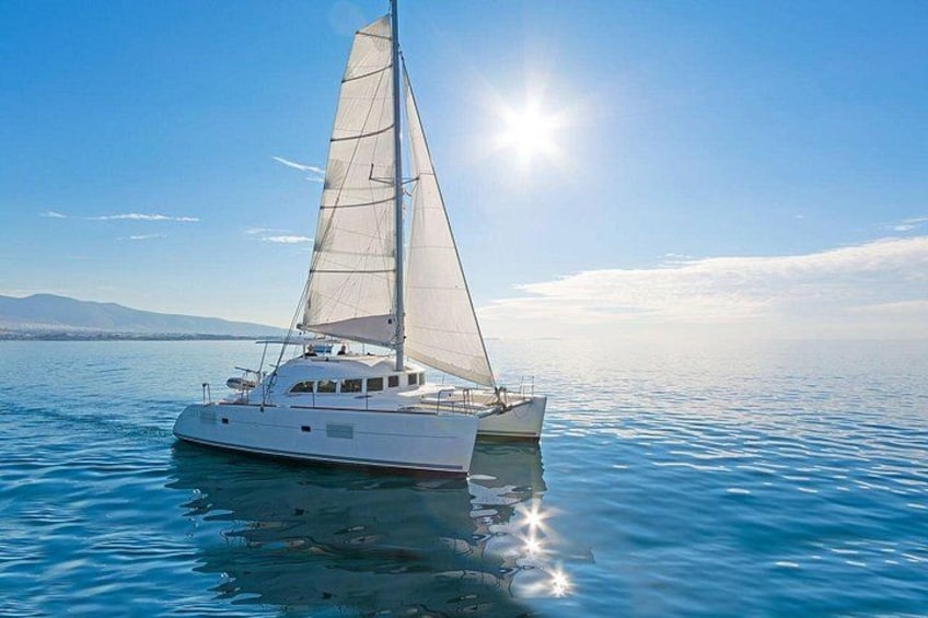 A white sailboat on calm blue waters with a clear sky and distant mountains. 2