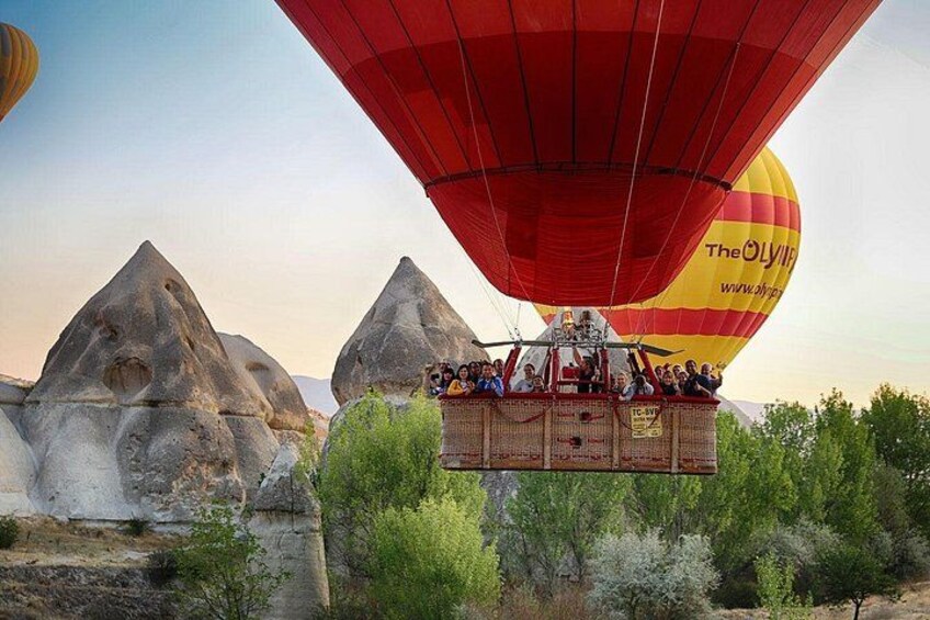 A hot air balloon with people on a platform, flying over a landscape with rock formations. 2