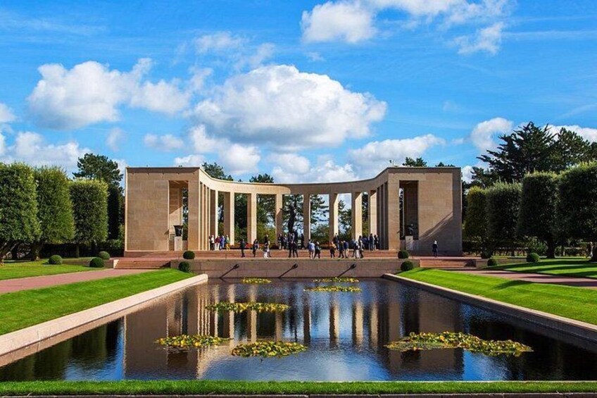 Une structure architecturale moderne, dotée de colonnes, d’un bassin d’eau décoratif et d’un jardin bien entretenu. 5