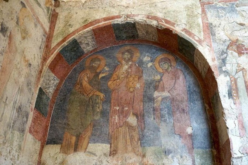 Een fresco met drie figuren in een halve cirkelvormige nis. 2