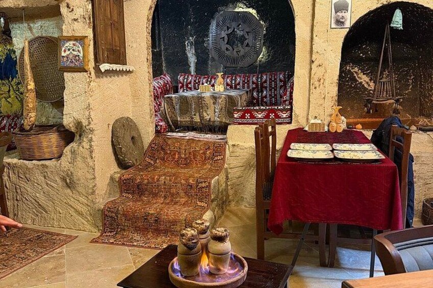 A traditional dining area with a red tablecloth, a wooden bench, and a decorative fountain. 3