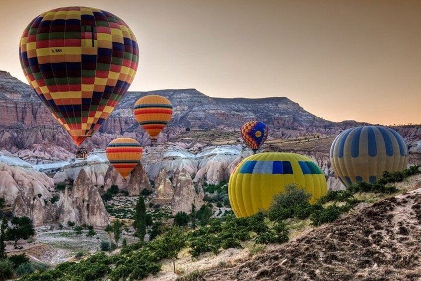 Hot air balloons in a rugged landscape with rocky formations and sparse vegetation. 5