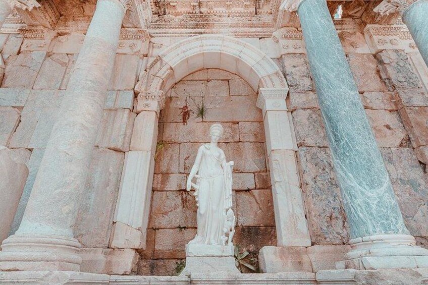 Una estructura arquitectónica clásica con una estatua central, flanqueada por columnas y una entrada arqueada. 1