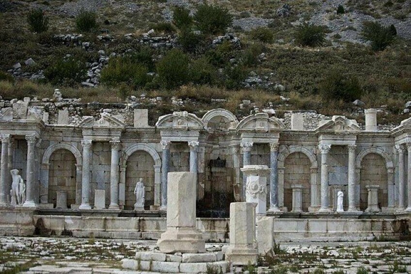 Ruinas antiguas con columnas y estatuas, al pie de una ladera. 4