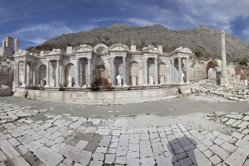 Ruinas antiguas con columnas y estatuas, con montañas al fondo. 2