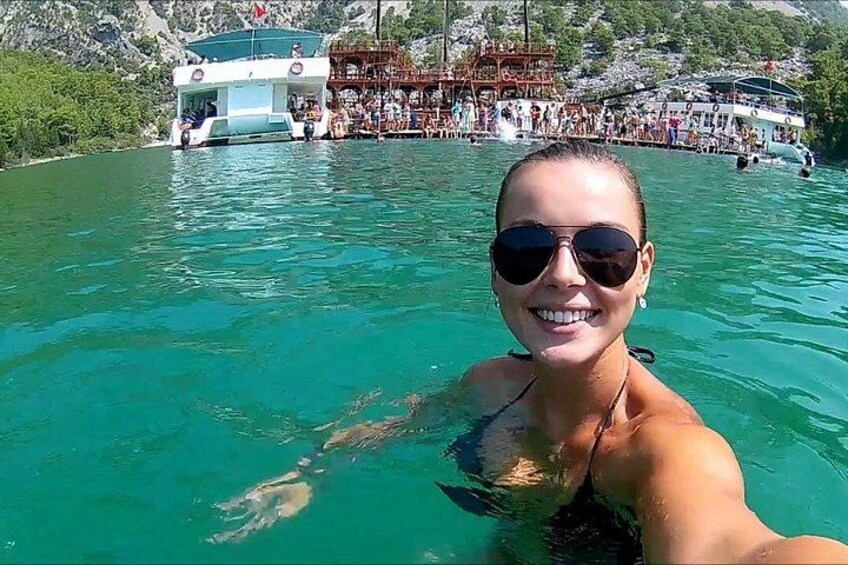Una persona nada en aguas cristalinas, con un bote y una multitud de fondo. 5