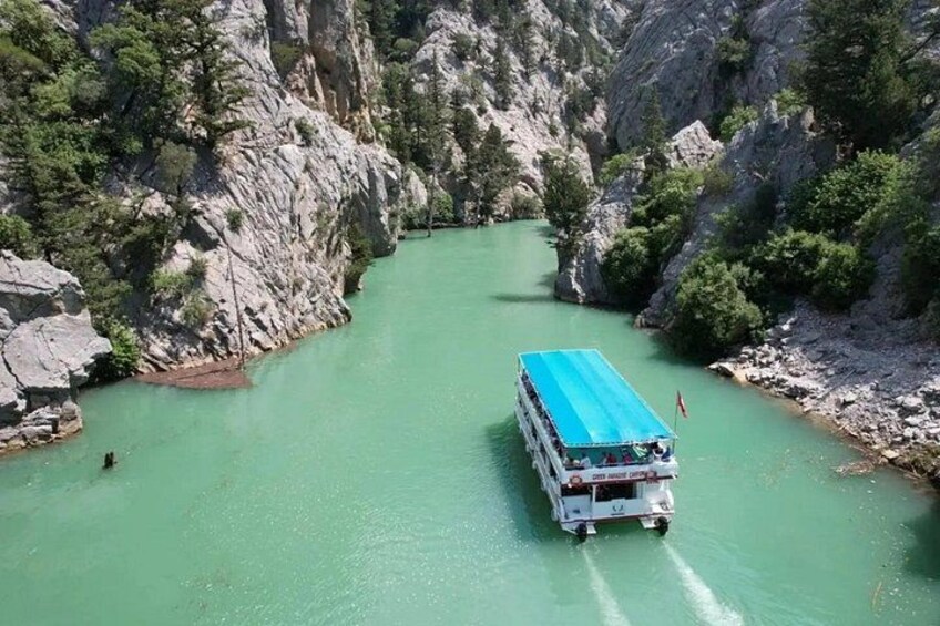 Una barca en un río turquesa rodeada de acantilados rocosos y vegetación. 4