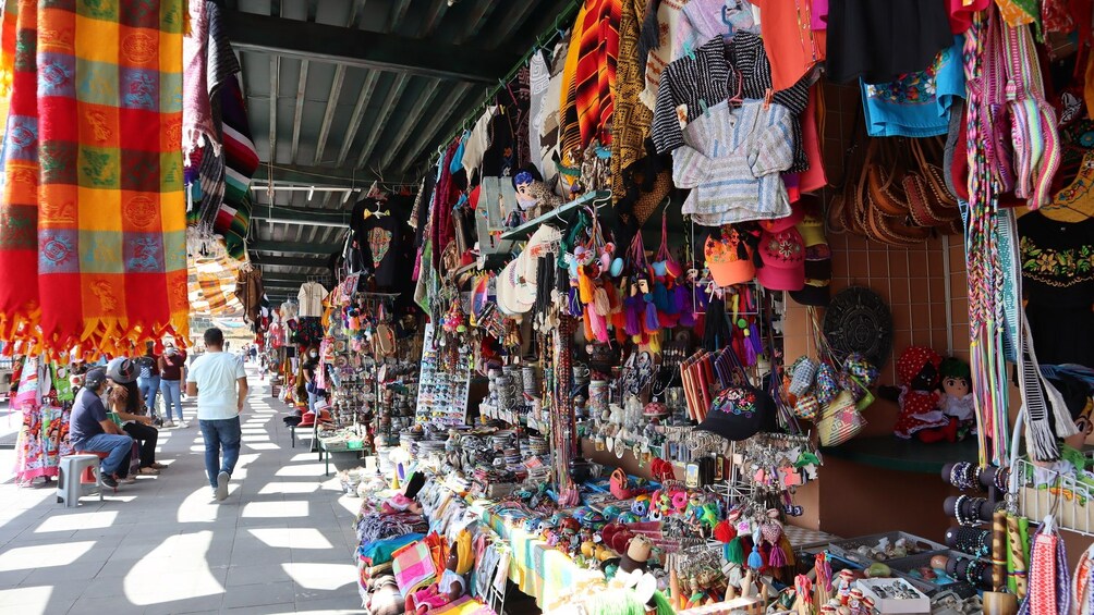 A bustling market with various stalls selling colorful textiles, bags, and accessories. 5