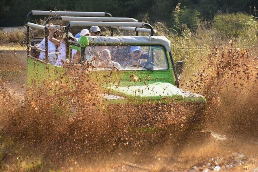 A green vehicle driving through a field with people inside. 4
