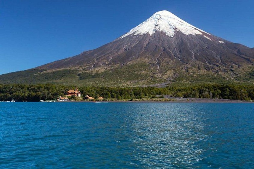 A snow-capped mountain, a body of water, and a small settlement with buildings. 1
