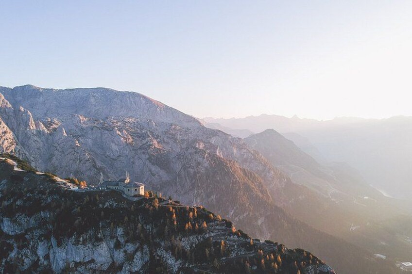 A mountainous landscape with a small building on a ridge. 1