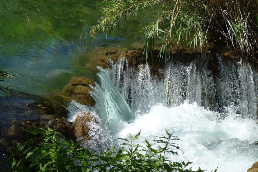 A waterfall cascading over rocks, surrounded by greenery. 3