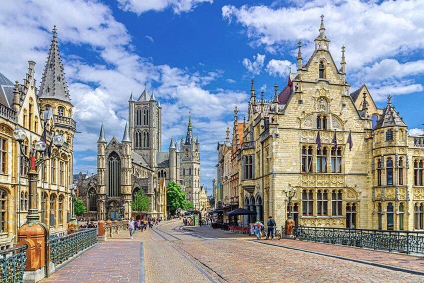 A cobblestone street with historic buildings, a church, and a bridge. 3